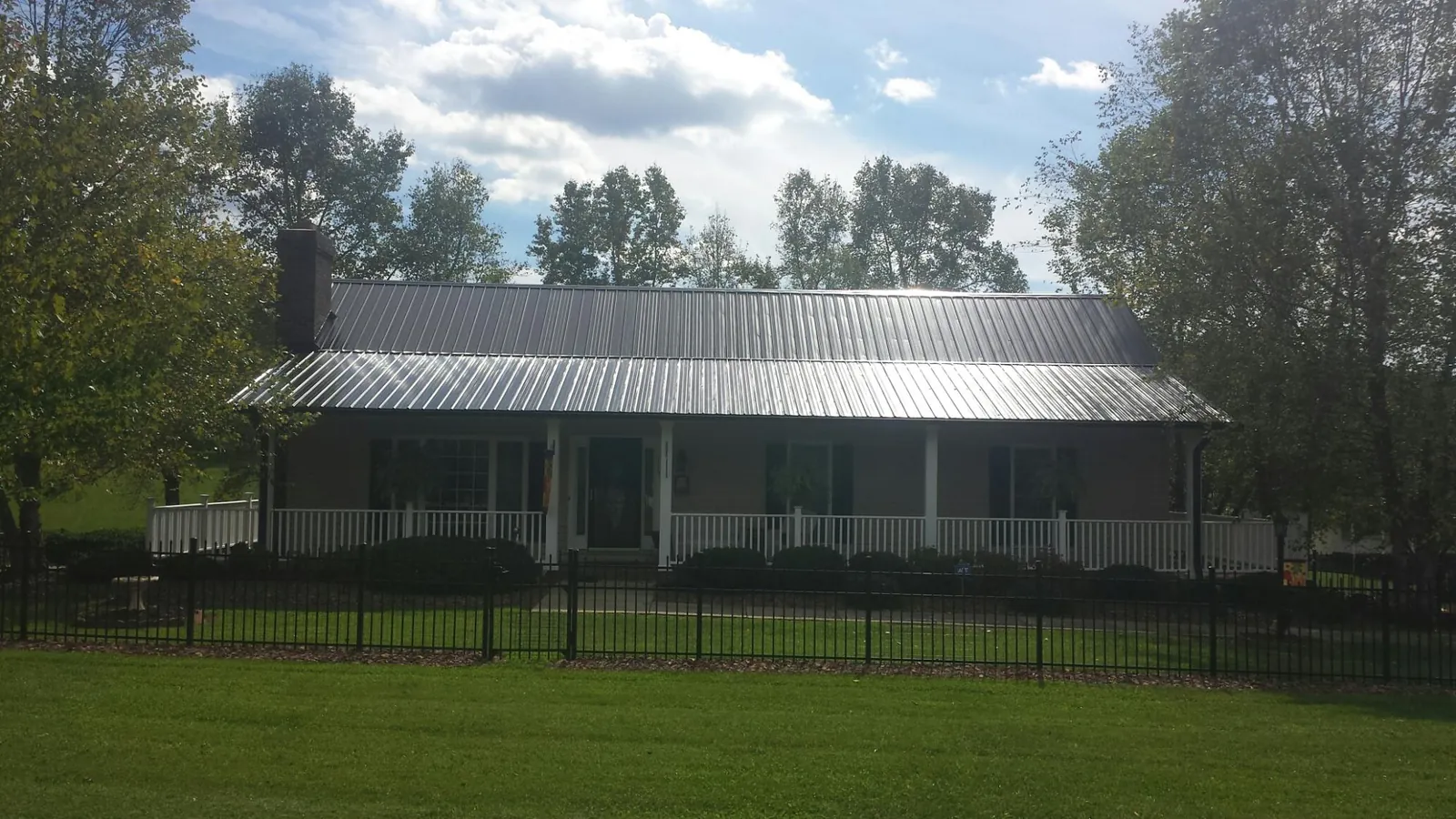 Gray metal roof on a brick ranch with a full width front porch — Gutter Guard Installation work by our crew in Saint Charles
